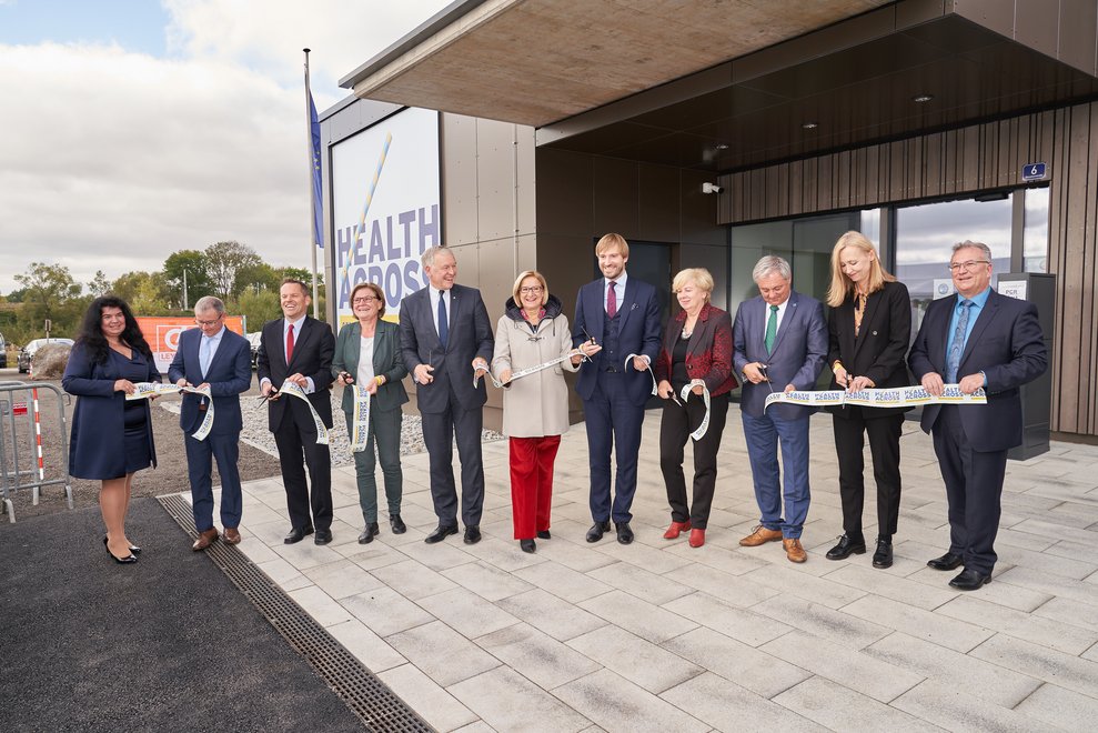 Eine Gruppe von Menschen eröffnet das Gesundheitszentrum und lächelt.